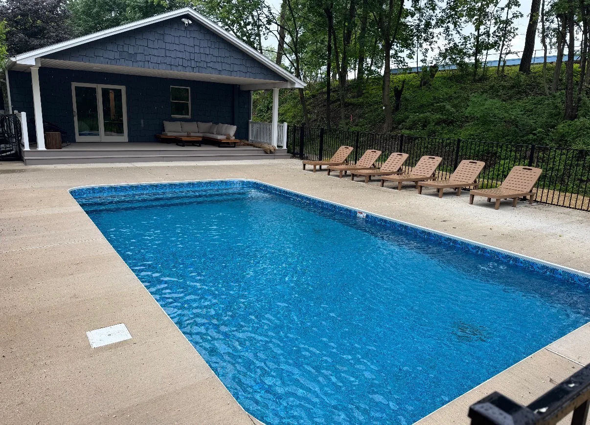 Finished patio and seating area beside a residential pool and pool house